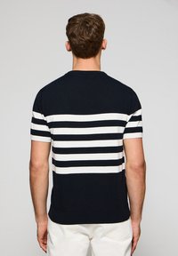 Marineblau-weiß gestreifter kurzärmeliger Strickpullover mit runder Halsausschnitt und geripptem Saum, der eine glatte Textur und einen lässigen Schnitt aufweist.