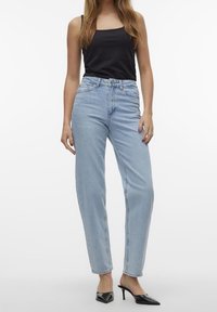 Ljusblå, högmidjade jeans med rak passform, som har fem fickor och en subtil denimstruktur, tillsammans med en svart linne.