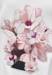 Gezicht van een vrouw omringd door grote roze en witte bloemen en vlinders, met de tekst "echt van hart" op haar nek.