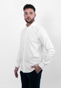 Witte button-up overhemd met lange mouwen en een klassieke kraag. Glad, lichtgewicht materiaal met een getailleerd ontwerp, gecombineerd met donkere broek.