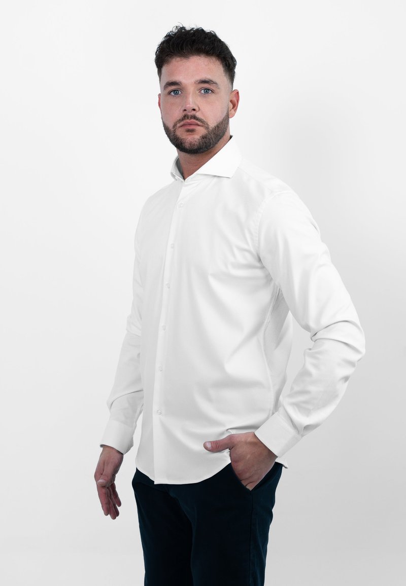 Witte button-up overhemd met lange mouwen en een klassieke kraag. Glad, lichtgewicht materiaal met een getailleerd ontwerp, gecombineerd met donkere broek.