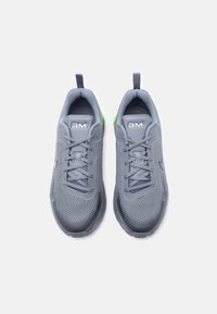 Ζευγάρι γκρι αθλητικά παπούτσια με πλέγμα στο πάνω μέρος, κορδόνια και θηλιές, σε φωτογραφία από πάνω με λε υκό φόντο.