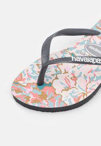 Chinelo com um padrão floral em rosa, azul e bege. As tiras pretas em borracha apresentam detalhes texturizados. A sola preta proporciona amortecimento.