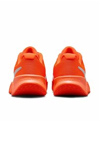 Scarpe da ginnastica di un vivace arancione, con tomaia in tessuto testurizzato, tacco imbottito e suola in gomma con un motivo a zigzag. Presenti dettagli argentati.