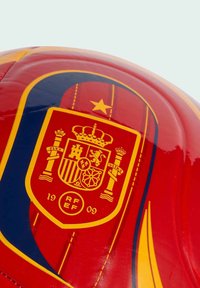 Crvena i žuta nogometna lopta s grbom španjolske reprezentacije, s krunom, stubovima i emblemom "RFEF 1909".