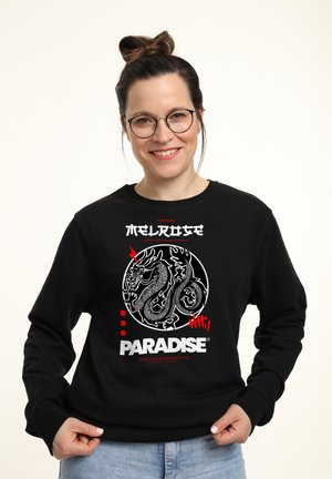 Schwarzes Sweatshirt mit einem weißen und roten Grafik eines Drachen sowie dem Text "MELROSE" und "PARADISE". Weicher Stoff mit klassischem Rundhalsausschnitt.