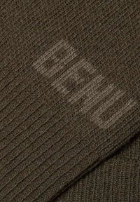 Donkerbruin geribbeld breisel met een subtiele textuur. Bevat een vervaagd logo patroon dat in het ontwerp is geïntegreerd.