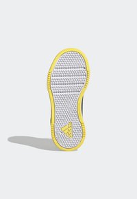 Suela exterior de zapatilla Adidas en blanco, con un patrón hexagonal, detalles amarillos a lo largo de los bordes y la marca en el lateral.