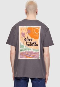 Grå T-shirt med korte ærmer, der har et farverigt surf-tema grafisk design på ryggen med palmer og bølger, trykt design detaljer.