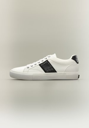 Baskets basses blanches avec panneau latéral texturé noir et languette de talon noire, lacets blancs et logo "GUESS" sur le panneau latéral.