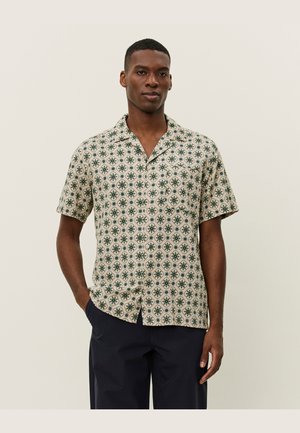 Short-sleeve shirt in beige fabric featuring a green floral pattern. Notable details include a collared neckline and button-down front.
