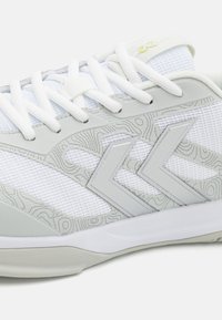 Weiße Sportschuhe mit einem Obermaterial aus Mesh, grauen Akzenten und einem strukturierten Muster an der Seite. Verfügen über weiße Schnürsenkel und eine gepolsterte Sohle.