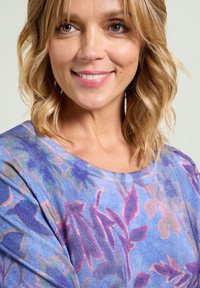 Top leggero con motivo floreale che presenta tonalità di blu, rosa e viola. Collo rotondo e maniche corte. Texture del tessuto morbida.