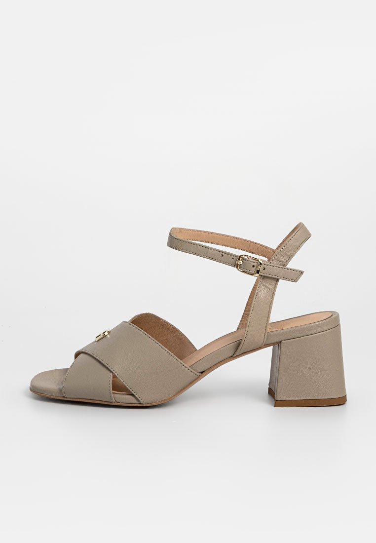 Beige Leder-Sandaletten mit einem Überkreuz-Riemen-Design, Knöchelriemen und einem niedrigen Blockabsatz. Verfügt über einen Schnallenverschluss und eine glatte Oberfläche.