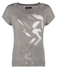 Šedé tričko s texturovaným povrchem, které má na přední straně geometrický bílý grafický design včetně pruhů a šipek, a kulatý výstřih.