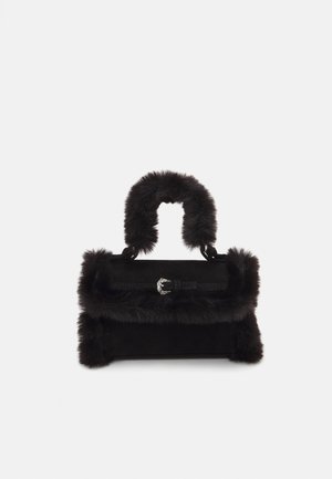 Schwarze Handtasche aus Wildleder mit Kunstfellbesatz. Sie verfügt über einen flauschigen Griff und eine dekorative silberne Schnalle an einem strukturierten Riemen.