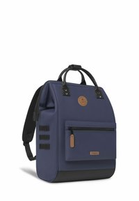 Zaino blu navy con una texture liscia, maniglie superiori, spallacci regolabili, tasca frontale con zip e una patch con logo; presenta accenti neri.