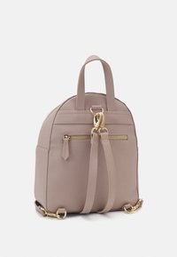 Kulbatý, světle béžový batoh z texturovaného materiálu, s zlatými zipy a kováním, dvojitými horními úchyty a nastavitelnými popruhy.