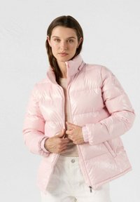 Giacca rosa puffosa con colletto alto, chiusura a zip e polsini elastici. Realizzata in materiale lucido e imbottito, progettata per calore e comfort.