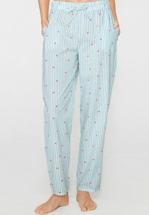 Hellblaue und weiße gestreifte Pyjamahosen mit kleinen pinkfarbenen Herzmustern, Tunnelzug in der Taille, barfuß getragen mit den Händen in den Taschen.