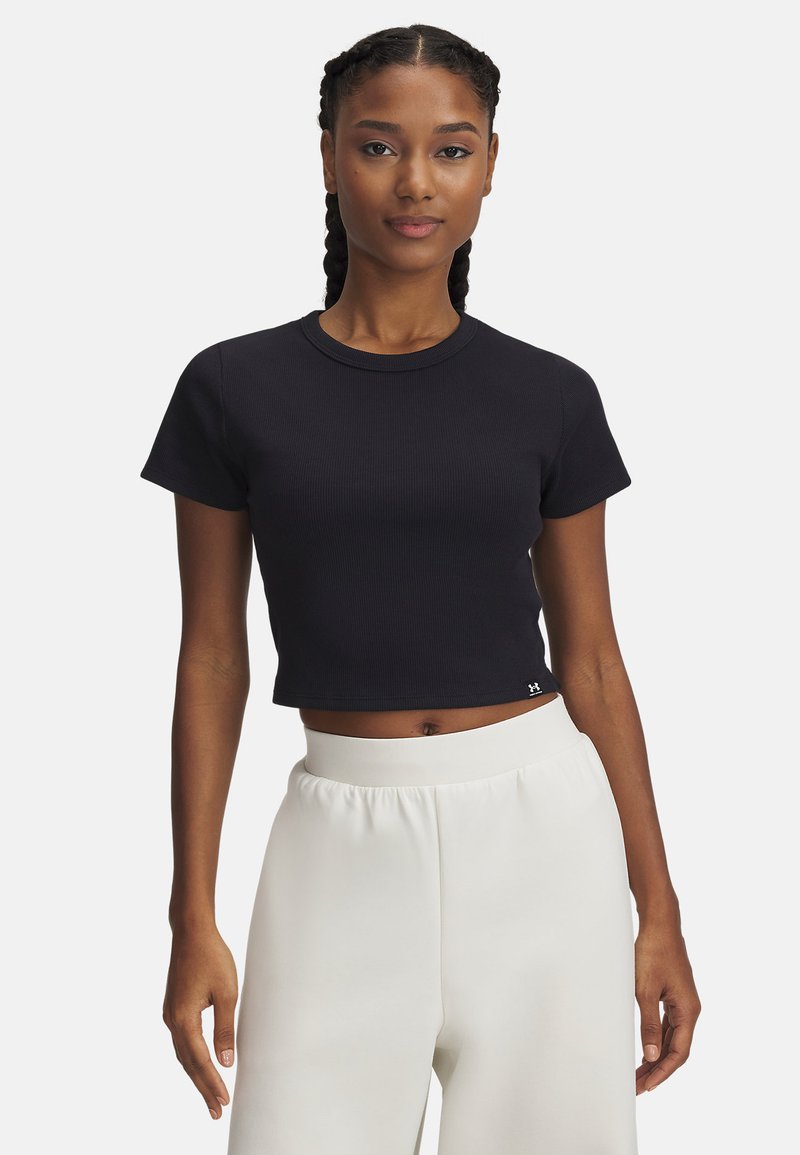 Black ribbed crop top with short sleeves and a round neckline, paired with white high-waisted loose-fitting pants. Subtle logo detail at hem.