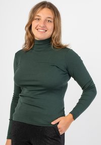 Maglietta verde a maniche lunghe con collo alto, dal design aderente, realizzata in tessuto liscio, dotata di orlo dritto e dettagli testurizzati sulle maniche.