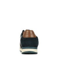 Sneaker en daim bleu foncé avec un talon en cuir marron, semelle couleur crème et couture décorative sur le côté. Tige texturée et accents lisses.