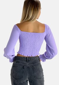 Lila lange mouwen crop top met een gerimpelde textuur, vierkante halslijn en gerufflede manchetten. Gekozen met een hoge taille zwarte jeans.
