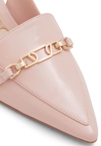 Chaussure en cuir verni rose à bout pointu, dotée d'une large bride avec un détail en chaîne dorée et d'une finition lisse.