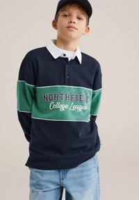 Laivastonsininen ja vihreä pitkähihainen poolopaita, jossa valkoinen kaulus, tekstillä "NORTHFIELD College League" ja napit kaula-aukossa.