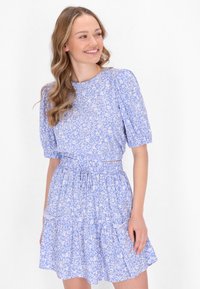 Blaues Blumenkleid mit Puffärmeln, elastischem Bund und gestuftem Rock. Der Stoff hat eine leichte Textur mit weißen Blumenmustern überall.