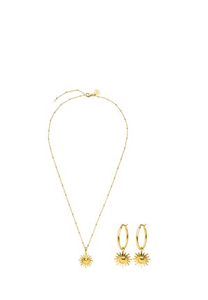 Goldene Halskette mit sonnenförmigem Anhänger und passenden Sonnen-Charme-Creolen vor weißem Hintergrund.