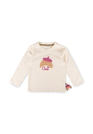 T-shirt crème à manches longues pour tout-petit avec petits points roses, applique d'un croissant souriant portant un béret violet, et texte rose "Oui" sur le devant.