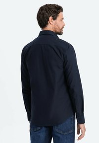 Camisa de hombre de manga larga azul marino oscuro con cuello clásico, detalle de yugo en la parte posterior y puños abotonados, hecha de una suave tela de mezcla de algodón.