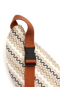 Borsa in tessuto con motivo zigzag a righe marroni e crema, con una fibbia scura e una tracolla brown regolabile. Materiale morbido, forma arrotondata.