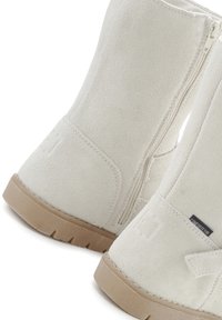 Stivaletti alla caviglia in suede bianco con zip laterale e suole in gomma beige. Caratterizzati da un design minimalista e un'etichetta con il marchio sul lato.