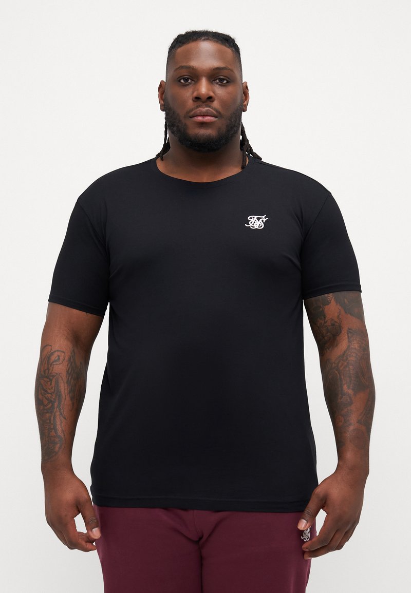 Tricou scurt, negru, din bumbac, cu guler rotund. Prezintă un mic logo alb pe pieptul stâng. Textură fină.