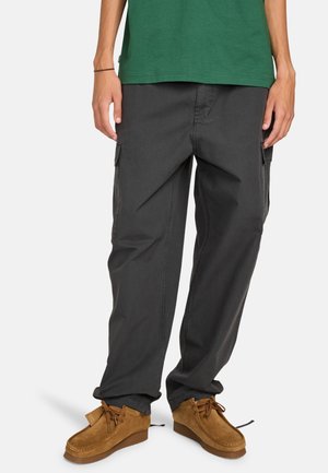 Gray cargo pants with a relaxed fit, two side pockets, and a textured fabric, paired with brown suede moccasins. Green t-shirt visible.