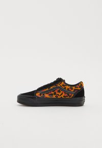 Svart mocka och mönstrad tygsneaker med orange och röd leopardtryck, svart gummisula och svarta snören.