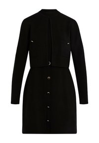 Vestido negro con una parte superior recortada y de manga larga. Presenta dos bolsillos en el pecho y una línea de botones en el frente, acentuada con detalles en dorado.