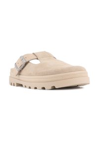 Beige semsket slip-on-sko med bred tå, justerbar spenne og teksturert gummisåle med spor for grep.