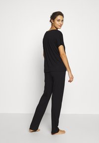 Black loungewear set featuring a loose-fit short-sleeve top and straight-leg pants, made from soft fabric, with a slight sheen.