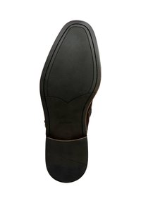 Suela de zapato negra con una superficie texturizada, que presenta una puntera redondeada y una sección suave y contorneada alrededor del talón. Logo de la marca visible.