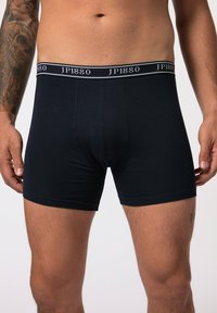 Black cotton boxer shorts with a fitted design. Features a branded elastic waistband and a smooth texture, with no visible patterns.