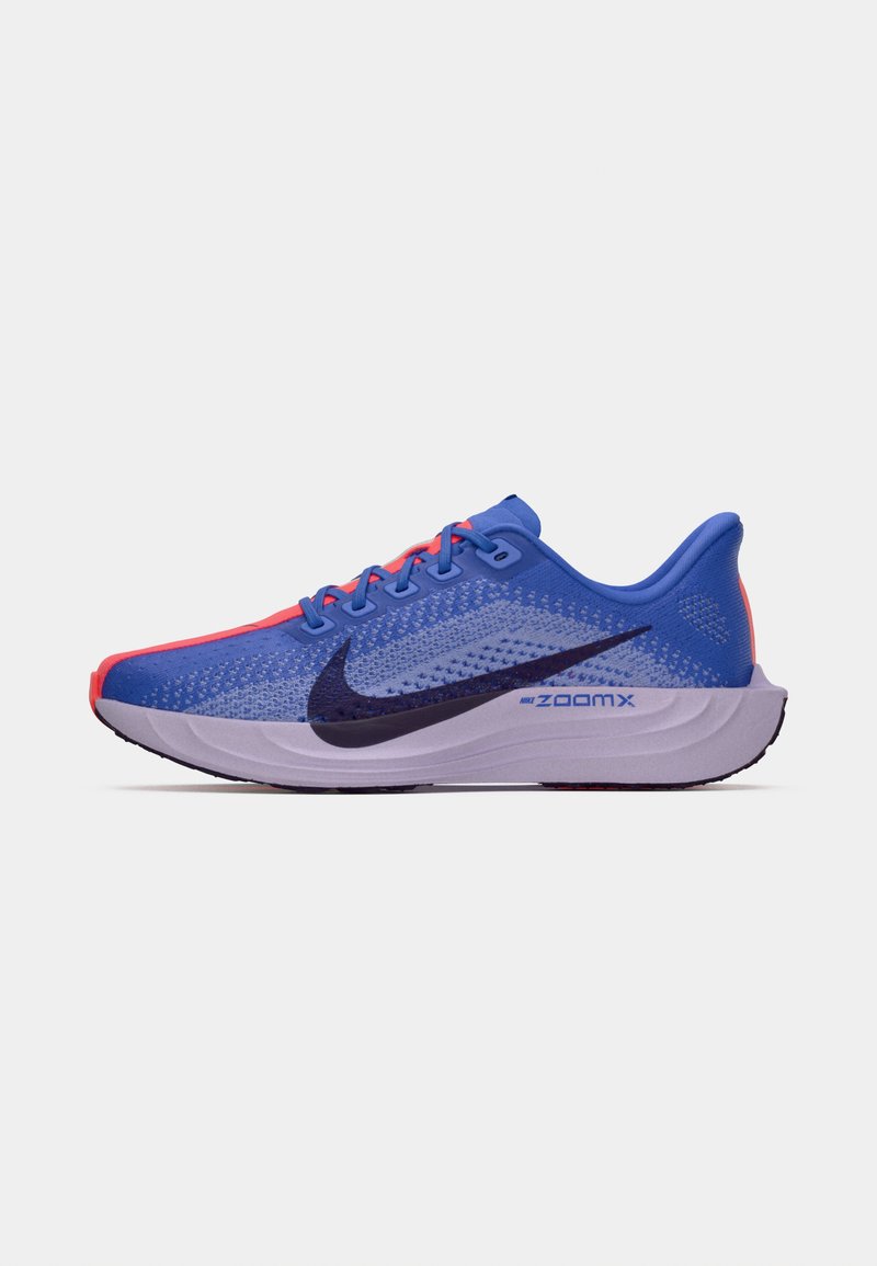 Zapatillas deportivas azules con una parte superior de malla transpirable, acentos rojos, un prominente swoosh negro y una suela gruesa de color claro marcada como "ZOOMX".