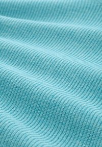 Strukturiertes Gewebe in hellem Türkis mit einem wellenförmigen Muster, das vertikale Rillen und eine weiche, leicht flauschige Oberfläche aufweist.