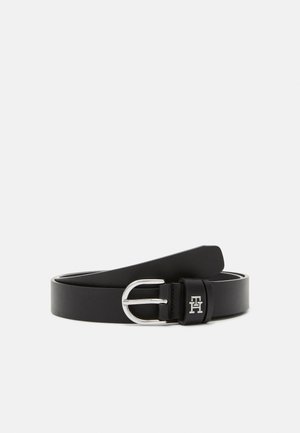 Ceinture en cuir noir avec boucle argentée et petit logo argenté « TH » sur la boucle de ceinture, présentée enroulée sur fond blanc.