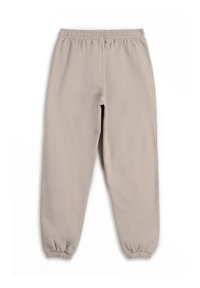 Jasno-beżowe spodnie jogger z elastycznym paskiem w talii i mankietami na końcach nogawek. Wykonane z miękkiego materiału, charakteryzują się gładką fakturą i luźnym krojem.