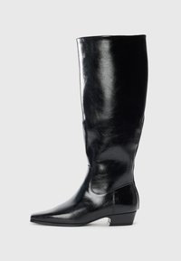 Bota de cuero negro hasta la rodilla con un acabado brillante, punta afilada y tacón bajo. Presenta una textura suave y un diseño minimalista.
