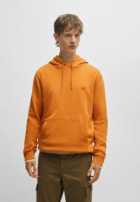 Oranje capuchon sweatshirt met een voorzak, ribgebreide zoom en logo label. Voorzien van lange mouwen en een zachte, gestructureerde stof.